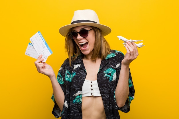 Mujer caucásica joven que sostiene boletos de avión muy felices.