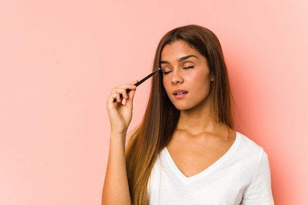 Mujer caucásica joven que sostiene un cepillo de ojos aislado