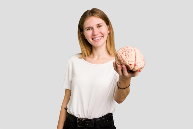 Foto mujer caucásica joven que sostiene un cerebro aislado