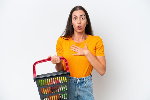 Mujer caucásica joven que sostiene una cesta de compras llena de comida