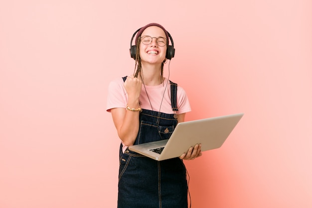 Mujer caucásica joven que sostiene una computadora portátil que anima despreocupado y emocionado. Victoria