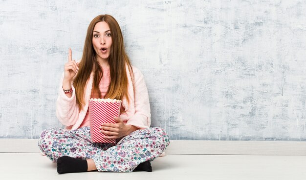 Mujer caucásica joven que sostiene un cubo de las palomitas de maíz que tiene una gran idea, concepto de creatividad.