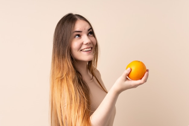 Mujer caucásica joven que sostiene una naranja