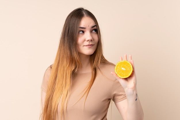 Mujer caucásica joven que sostiene una naranja