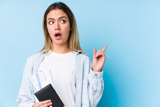 Mujer caucásica joven que sostiene un pasaporte aislado que señala al lado