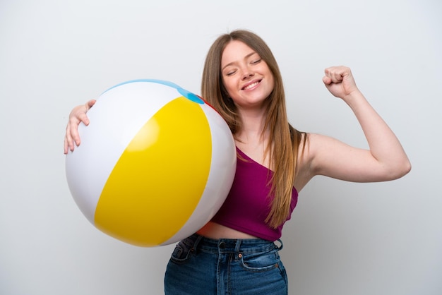 Mujer caucásica joven que sostiene la pelota de playa aislada en el fondo blanco que hace gesto fuerte