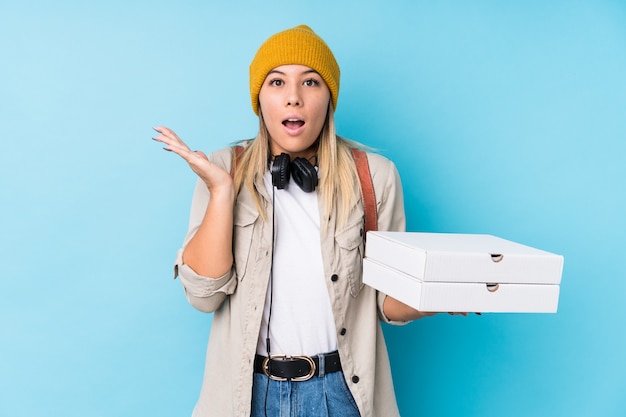 Mujer caucásica joven que sostiene las pizzas aisladas sorprendidas y conmocionadas.