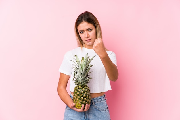 Mujer caucásica joven que sostiene un puño de la piña que muestra