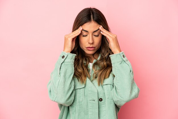 Mujer caucásica joven que toca las sienes y que tiene dolor de cabeza.