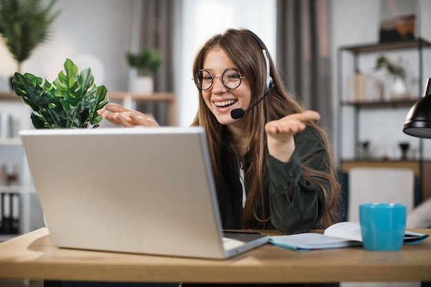 Mujer caucásica joven que usa auriculares y una computadora portátil para una conversación de video en la oficina