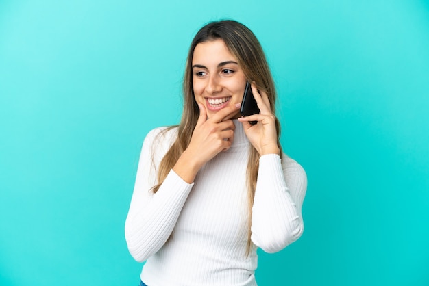Foto mujer caucásica joven que usa el teléfono móvil aislado en mirar hacia el lado y sonriendo