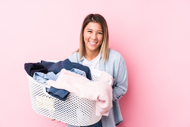 Mujer caucásica joven recogiendo una ropa sucia riendo y divirtiéndose.