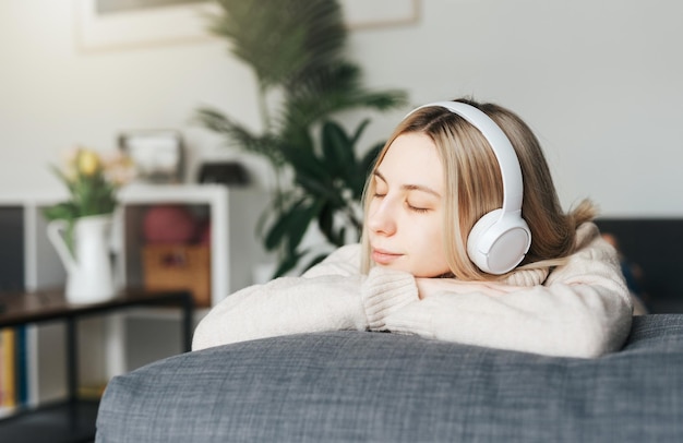 Mujer caucásica joven se relaja en casa con música