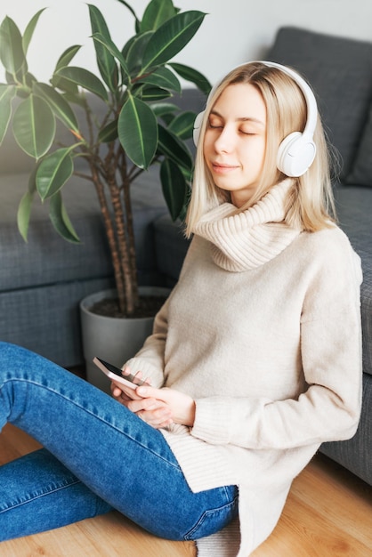 Mujer caucásica joven se relaja en casa con música