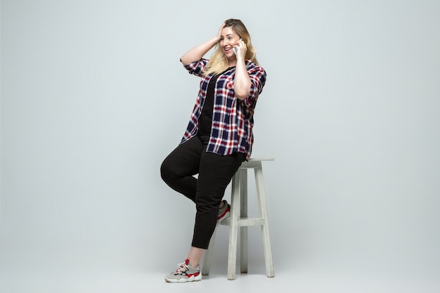 Mujer caucásica joven en ropa de sport sobre fondo gris. Personaje femenino corporal positivo, talla grande