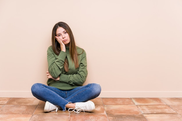 Foto mujer caucásica joven sentada en el suelo aislada que está aburrida, fatigada y necesita un día de relax.