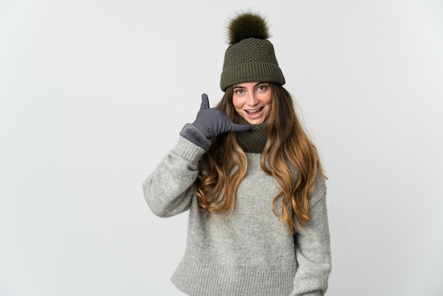 Mujer caucásica joven con sombrero de invierno aislado en blanco haciendo gesto de teléfono. Llámame señal