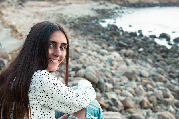 Mujer caucásica joven sonriendo con una camisa blanca en la playa