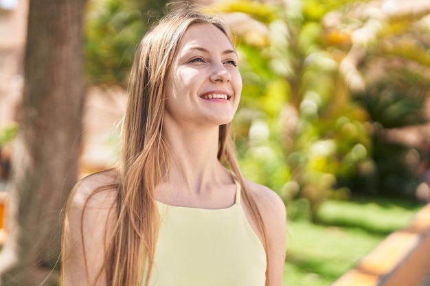 Mujer caucásica joven sonriendo confiada mirando hacia un lado en el parque