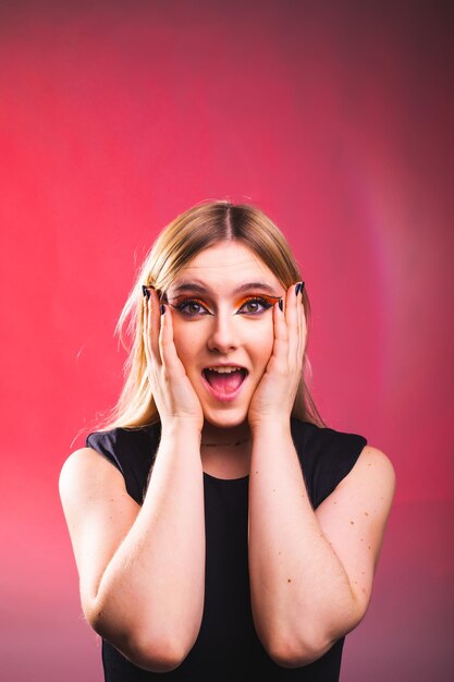 Mujer caucásica joven sorprendida en un estudio de fotografía con un fondo rojo.