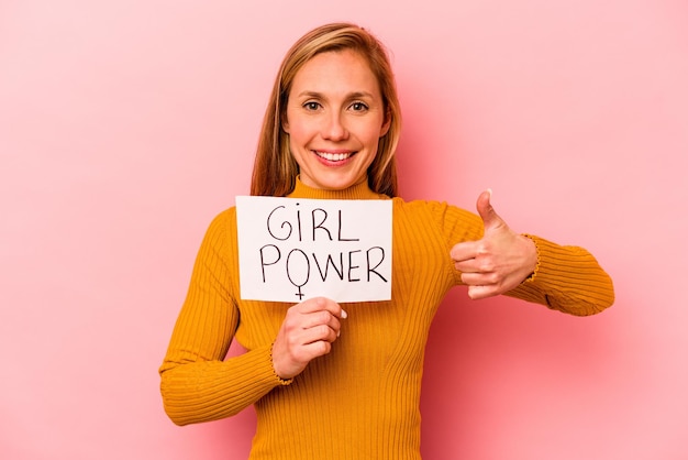 Mujer caucásica joven sosteniendo cartel de poder femenino aislado sobre fondo rosa