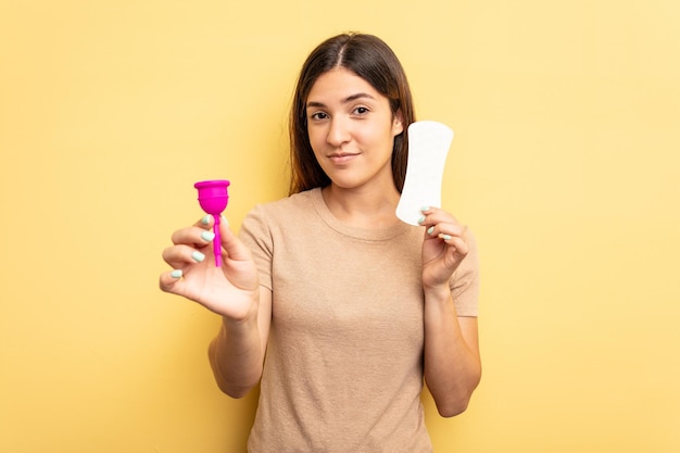 Mujer caucásica joven sosteniendo una copa menstrual aislada sobre fondo amarillo