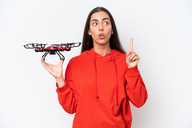 Mujer caucásica joven sosteniendo un dron aislado sobre fondo blanco.