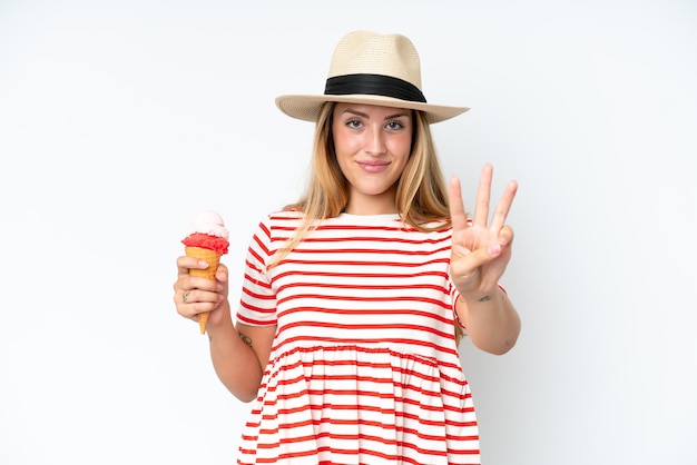 Mujer caucásica joven sosteniendo un helado de cucurucho aislado sobre fondo blanco feliz y contando tres con los dedos