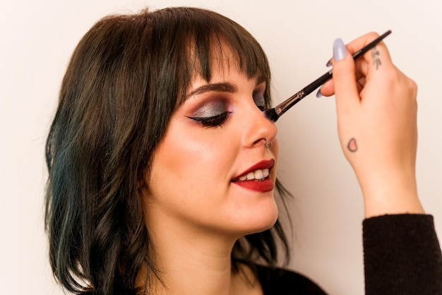 Mujer caucásica joven sosteniendo pincel de maquillaje aislado sobre fondo rosa