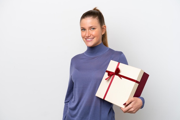 Mujer caucásica joven sosteniendo un regalo aislado sobre fondo blanco sonriendo mucho