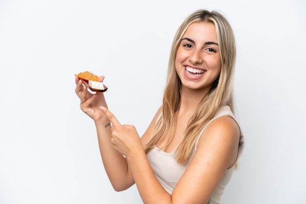 Mujer caucásica joven sosteniendo sashimi aislado sobre fondo blanco y apuntándolo