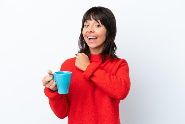 Mujer caucásica joven sosteniendo una taza de café aislada de fondo blanco celebrando una victoria