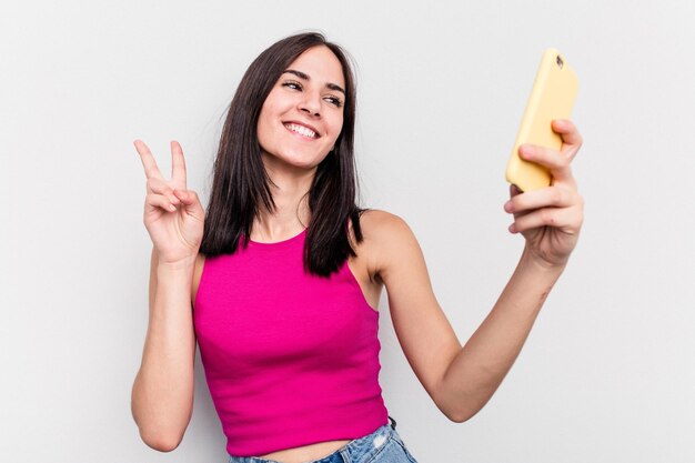 Mujer caucásica joven sosteniendo teléfono móvil aislado sobre fondo blanco.