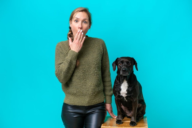 Mujer caucásica joven con su perro aislado sobre fondo azul con sorpresa y expresión facial conmocionada