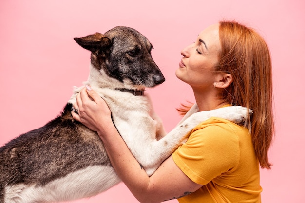 Mujer caucásica joven con su perro aislado sobre fondo rosa