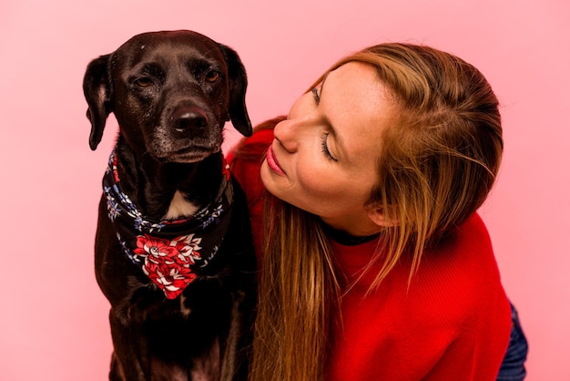 Mujer caucásica joven con su perro aislado sobre fondo rosa