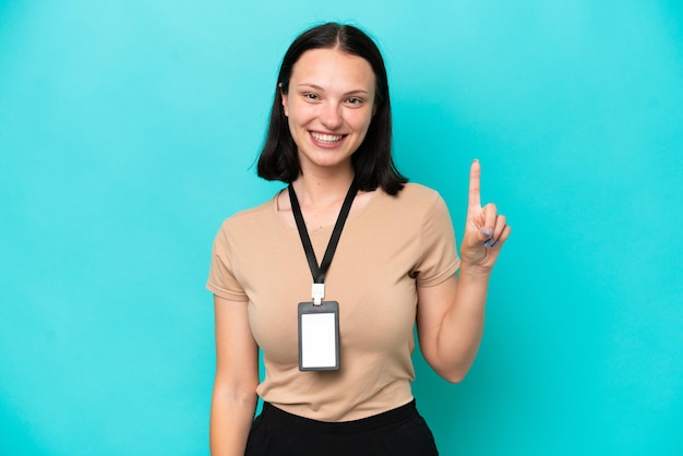 Foto mujer caucásica joven con tarjeta de identificación aislada de fondo azul señalando una gran idea