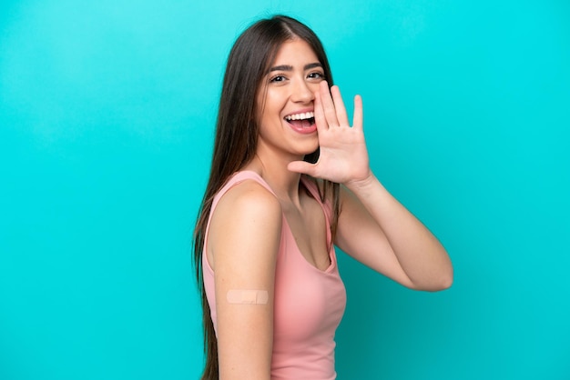 Mujer caucásica joven con tiritas aisladas de fondo azul gritando con la boca abierta