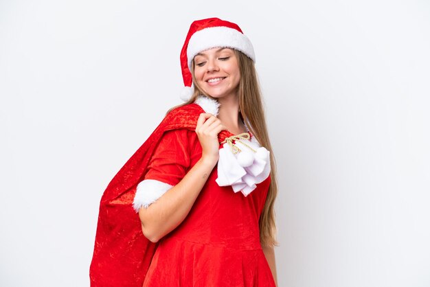 Foto mujer caucásica joven vestida como mamá noel sosteniendo saco de navidad aislado sobre fondo blanco con expresión feliz