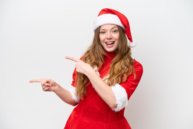 Mujer caucásica joven con vestido de Navidad aislado sobre fondo blanco sorprendido y apuntando hacia el lado