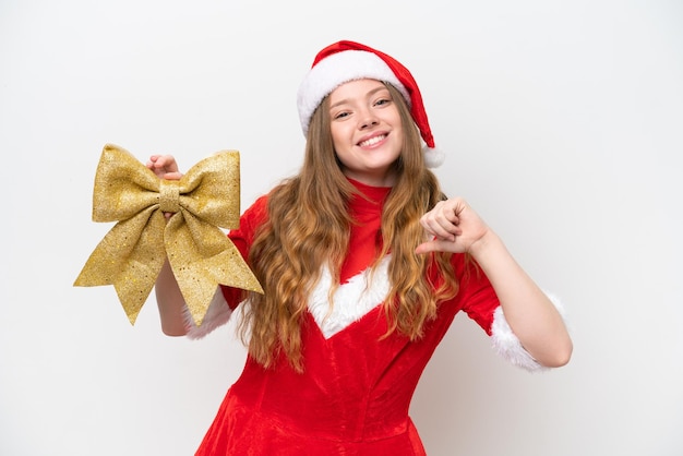 Mujer caucásica joven con vestido de Navidad con arco de Navidad aislado sobre fondo blanco orgullosa y satisfecha