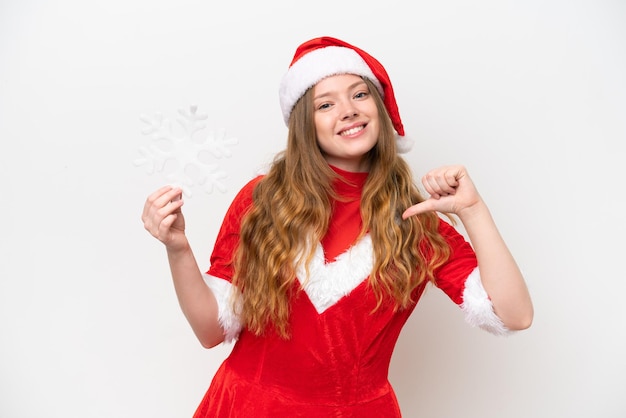 Mujer caucásica joven con vestido de Navidad sosteniendo copo de nieve aislado sobre fondo blanco orgullosa y satisfecha