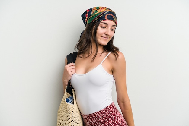 Mujer caucásica joven vistiendo una bolsa de playa aislado sobre fondo blanco.