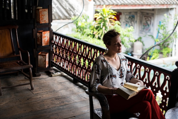 Mujer caucásica leyendo el libro en el balcón