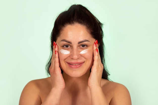 Foto mujer caucásica madura aplicando crema facial producto para el cuidado de la piel de 30 a 40 años de edad