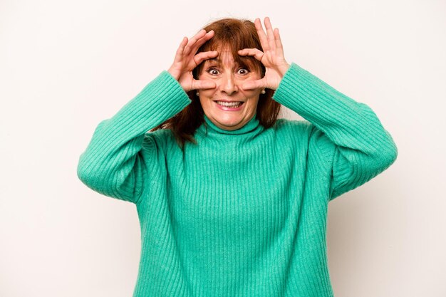 Mujer caucásica de mediana edad aislada de fondo blanco manteniendo los ojos abiertos para encontrar una oportunidad de éxito