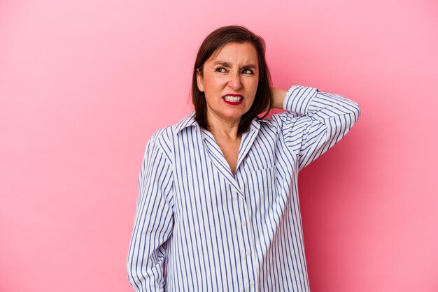 Mujer caucásica de mediana edad aislada de fondo rosa cansada y con mucho sueño manteniendo la mano en la cabeza.