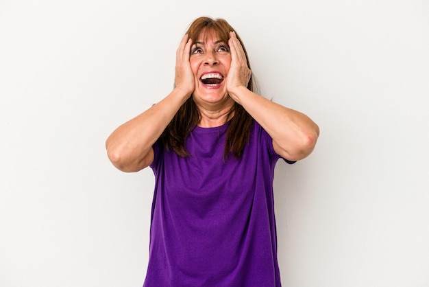 Mujer caucásica de mediana edad aislada sobre fondo blanco se ríe con alegría manteniendo las manos en la cabeza. Concepto de felicidad.