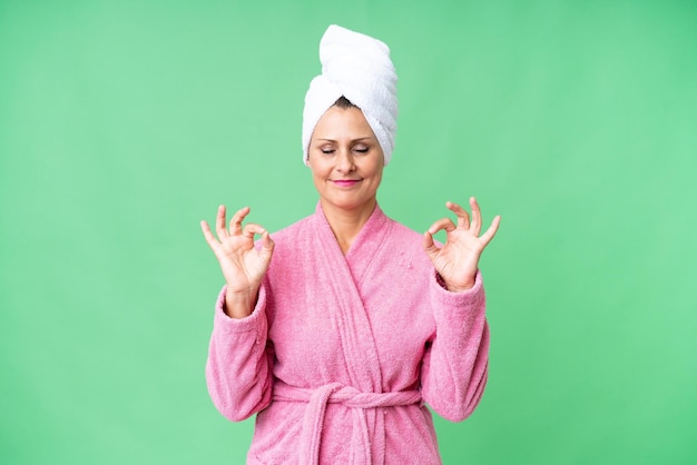 Mujer caucásica de mediana edad en bata de baño sobre fondo aislado en pose zen