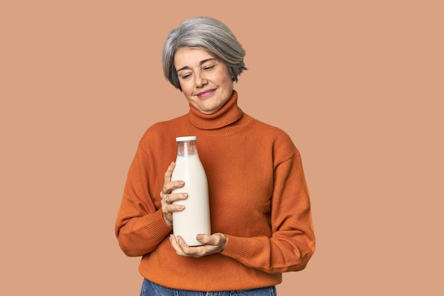 Mujer caucásica de mediana edad con una botella de leche feliz sonriente y alegre